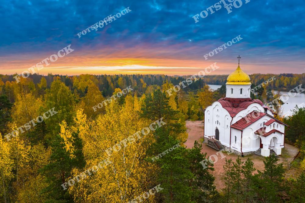 На фото изображена церковь, расположенная в Карелии, на фоне осеннего леса. Золотой купол церкви контрастирует с яркими оттенками осенних деревьев и мягким светом, исходящим от заходящего солнца. Этот архитектурный памятник является популярным объектом для туристов и паломников. Карелия знаменита своей природной красотой и историческими памятниками, которые притягивают путешественников со всего мира.